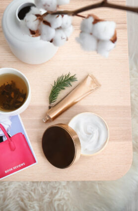 Composition with cosmetic products, magazine and tea on wooden table